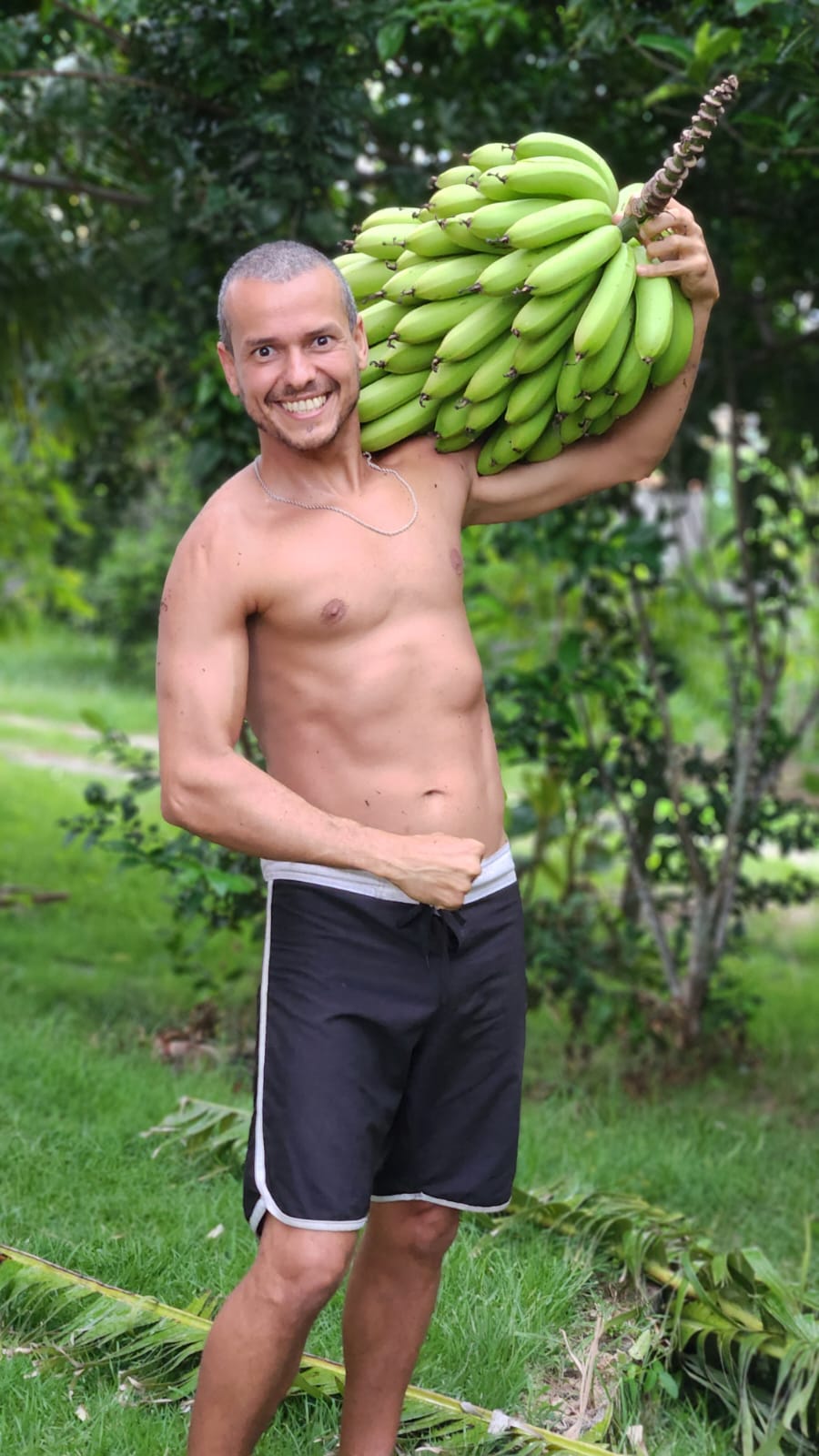 Dr. Corassa carregando cacho de banana no campo